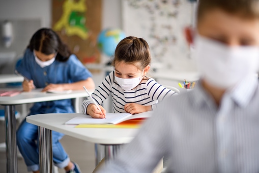 Enfants qui passe un examen avec un masque pour illustrer cet article sur l'anxiété des enfants en contexte de pandémie.